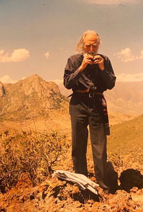 Gastón de pie en la cima de un cerro, con montañas detrás
