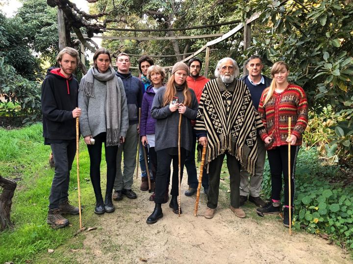 Gastón con poncho junto a un grupo con bastones de caminata